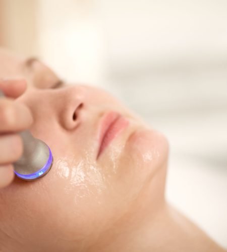 Close-up shot of woman getting professional facial treatment with special equipment. Cosmetician doing lifting procedure
